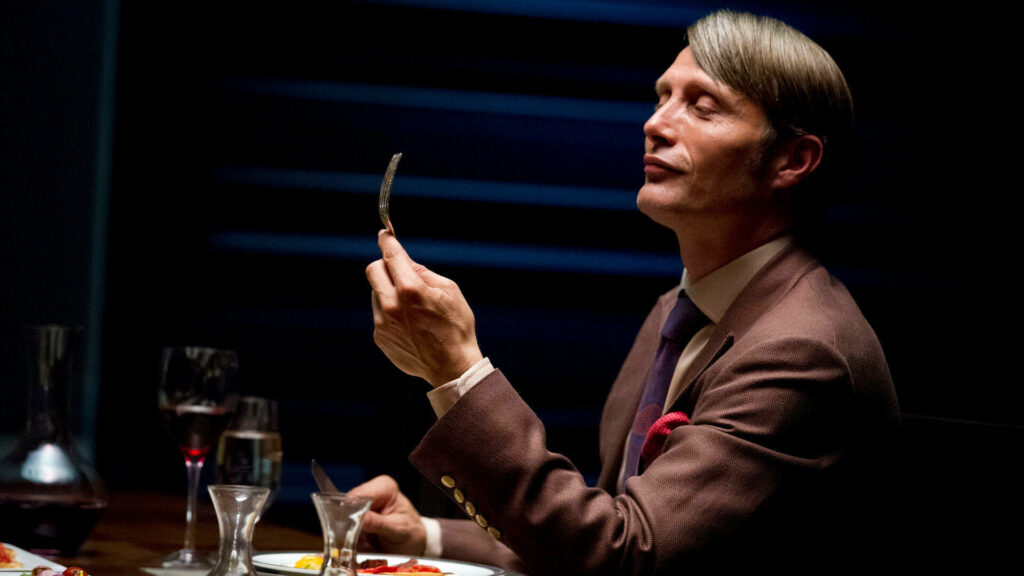 Passion of Arts: Hannibal sitzt am Tisch und schaut genussvoll auf seine Gabel