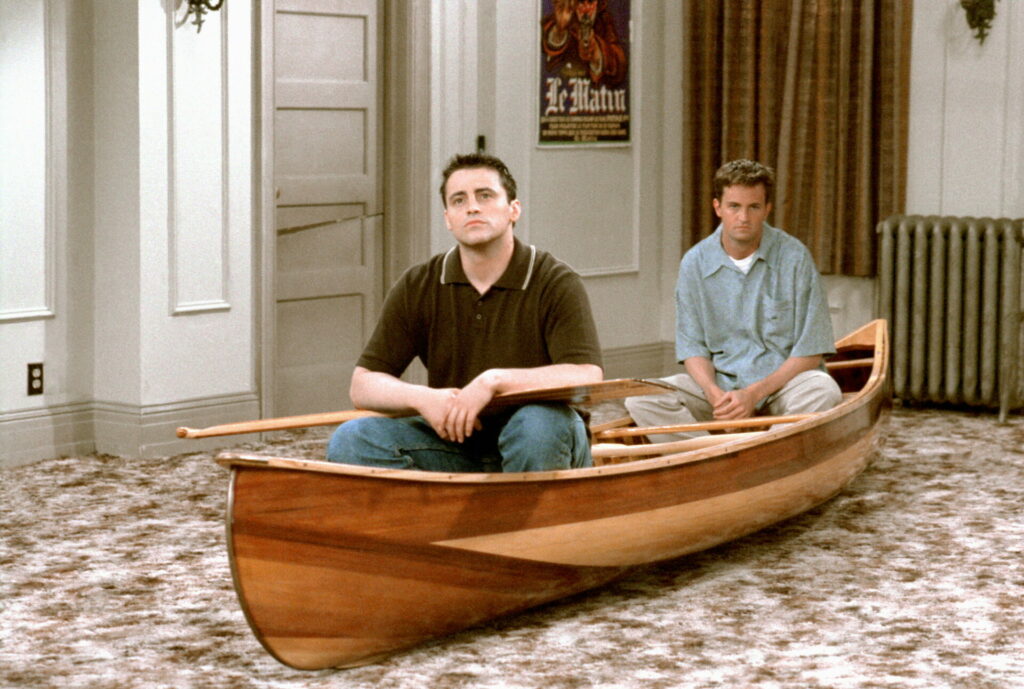 Passion of Arts: Joey und Chandler sitzen in einem Ruderboot im Wohnzimmer