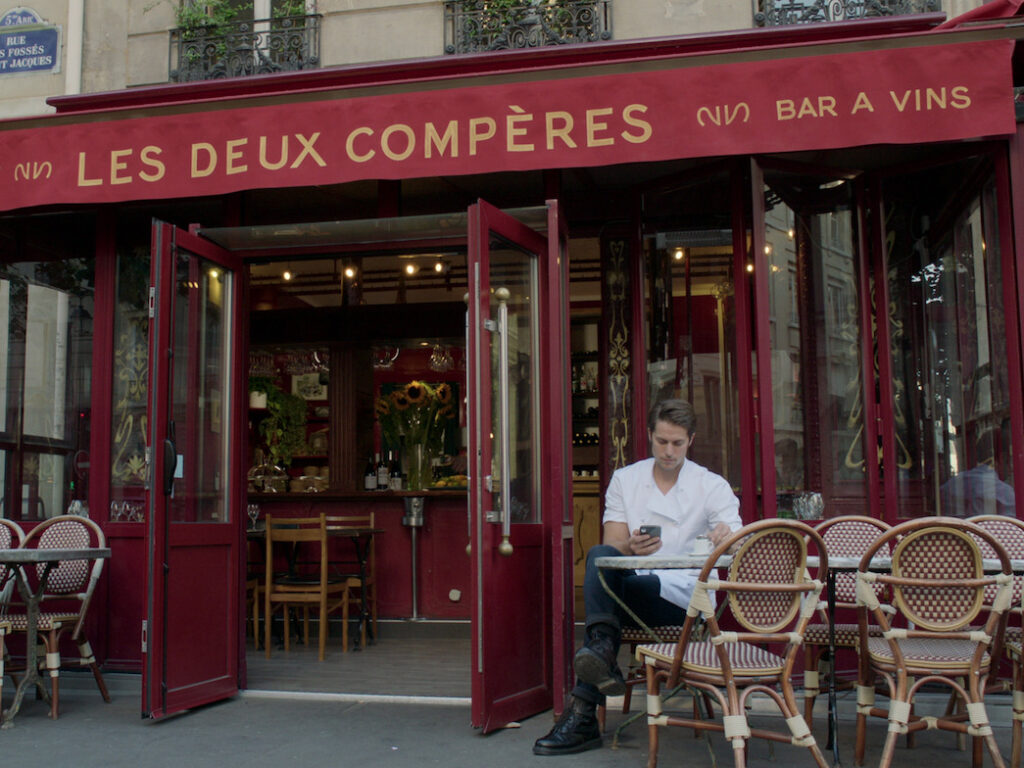 Passion of Arts: Gabriel sitzt vor seinem Restaurant "Les deux compères" und schaut in sein Handy