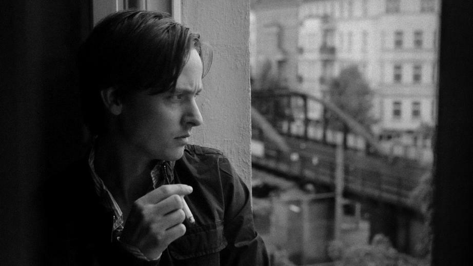 Passion of Arts: Der Antiheld Niko Fischer sitzt am Fenster und raucht eine Zigarette