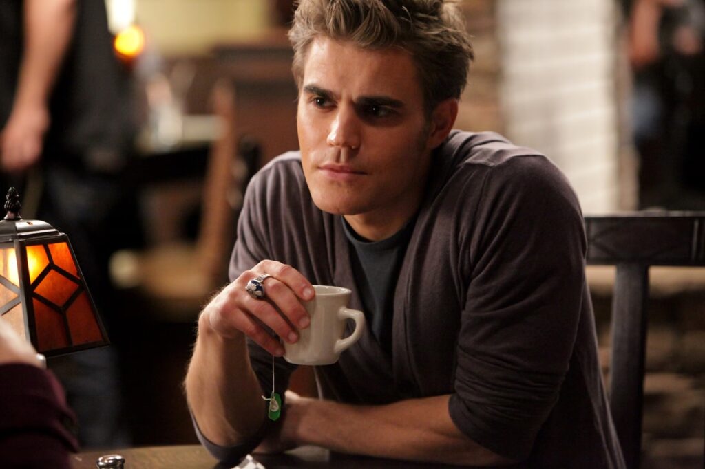 Passion of Arts: Stefan sitzt im Café und hält eine Teetasse in der Hand. Aus der Teetasse hängt ein Band des Teebeutels