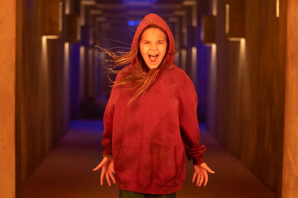 Passion of Arts Firestarter: Charlie McGee steht schreiend in einem Gang und trägt dabei einen roten Hoodie.