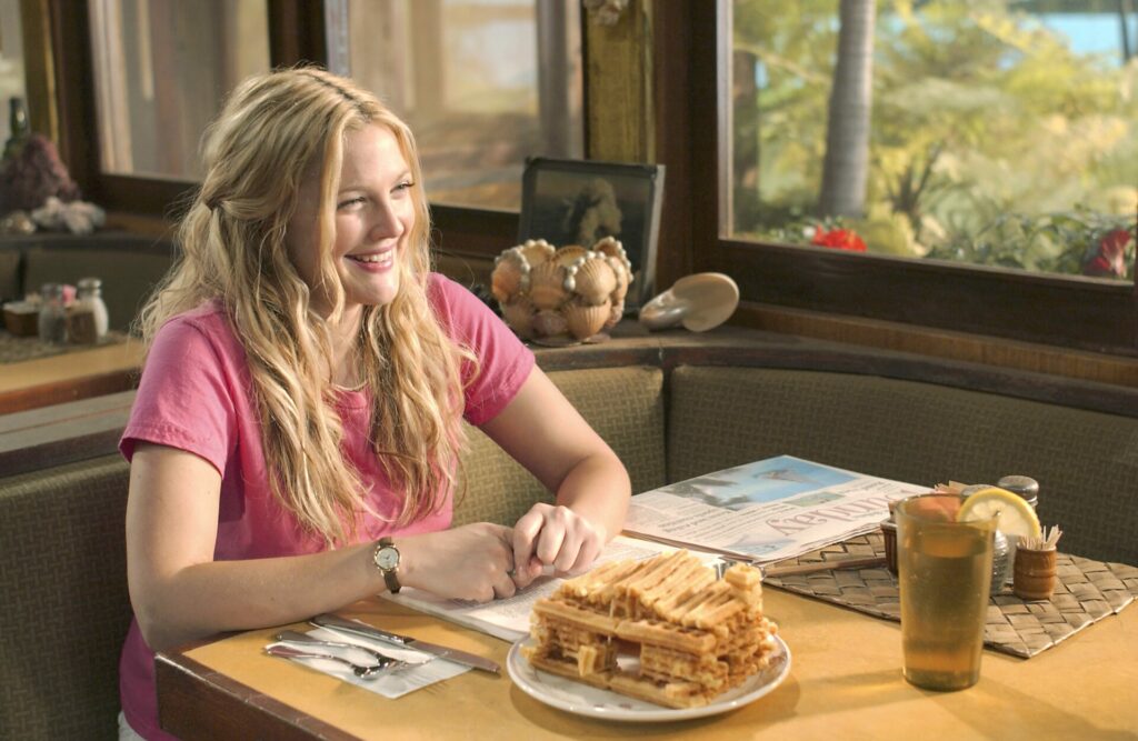 Passion of Arts: Lucy (Drew Barrymore) sitzt im Restaurant, vor ihr ein Haus, gebaut aus Waffeln und sie lacht
