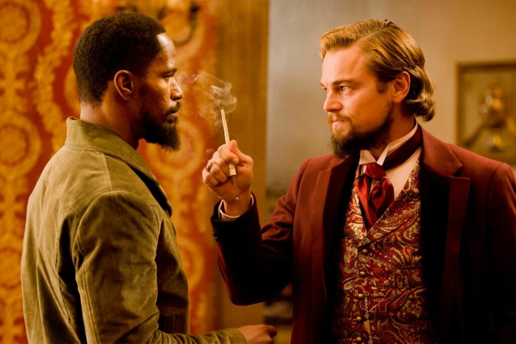 Links steht Django, er schaut Calvin Candy ins Gesicht, der ihm herausfordernd eine Zigarette vors Gesicht hält