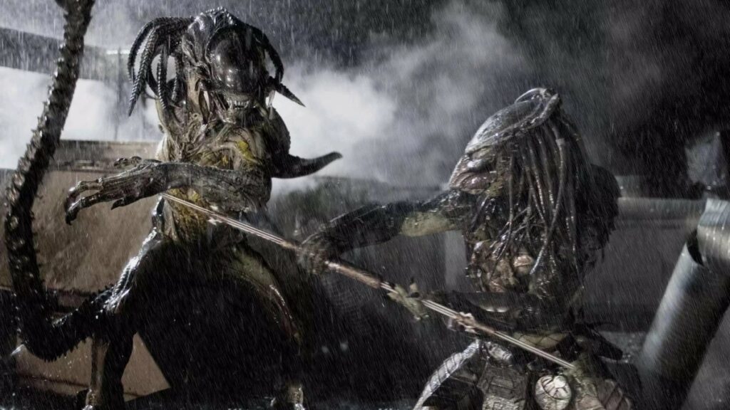 Auf dem Bild stehen Alien und Predator im Regen und bekämpfen sich gegenseitig. Predator sticht gerade mit einer Stahllanze auf Alien ein, dieses kann jedoch ausweichen