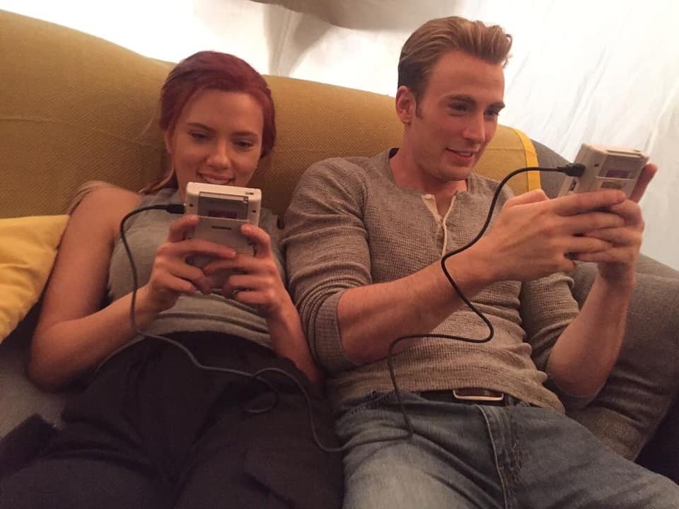 Film-Ensembles: Auf dem Bild ist links Scarlett Johansson und neben ihr sitzt Chris Evans. Beide gucken in einen Gameboy, die via Kabel miteinander verbunden sind