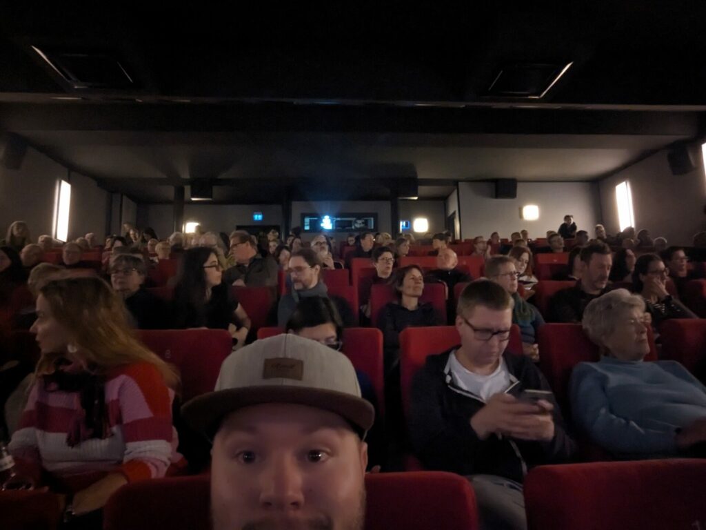 Braunschweig International Film Festival: Das Bild zeigt einen vollen Kinosaal. Vorne sitzt Lennart und schaut aufgeregt ins Bild