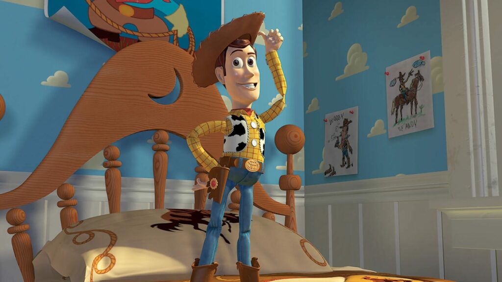 Auf dem Bild sieht man einen Spielzeugcowboy, der auf einem Kinderbett steht und sich lässig mit dem Daumen an den Hut tippt