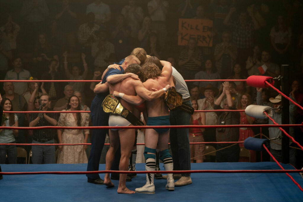The Iron Claw: Das Bild zeigt fünf Männer, die sich in einem Boxring eng umschlingen. Im Hintergrund ist ein jubelndes Publikum