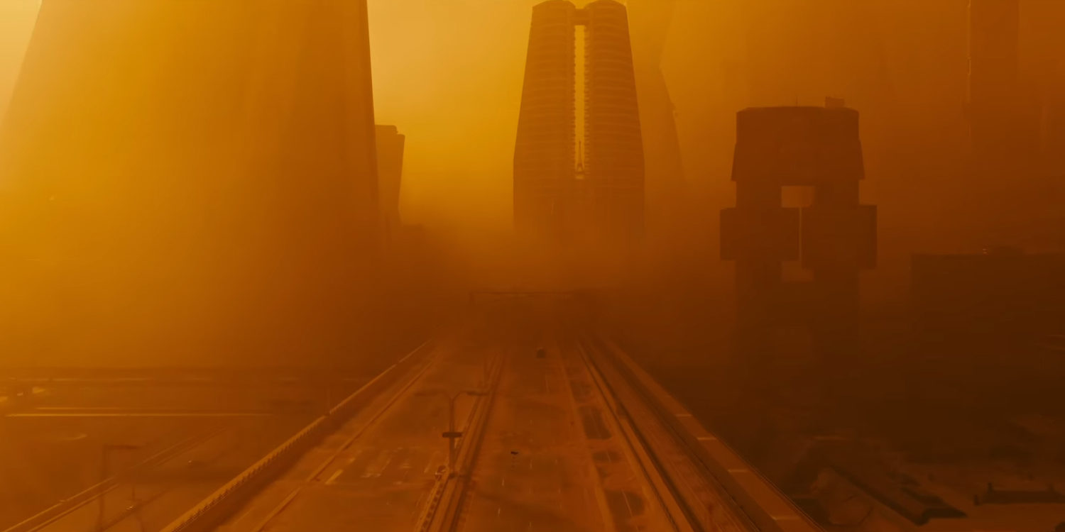 Blade Runner 2049: Das Bild zeigt eine Autobahn und eine Stadt. Die Umgebung ist vom orangen und gelben Nebel umgeben