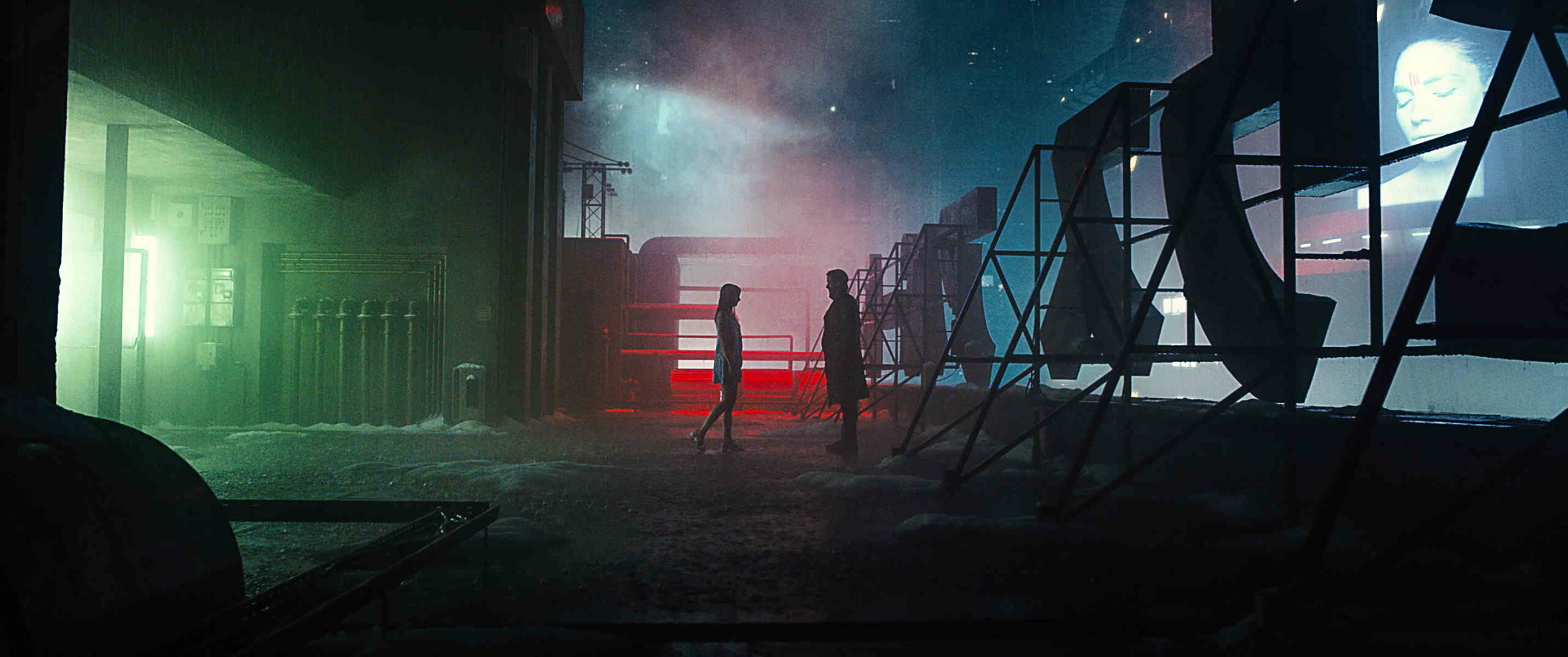 Das Bild zeigt einen Mann und eine Frau die sich gegenüber stehen. Sie sind hinter einer großen Buchstabentafel im Neon Licht