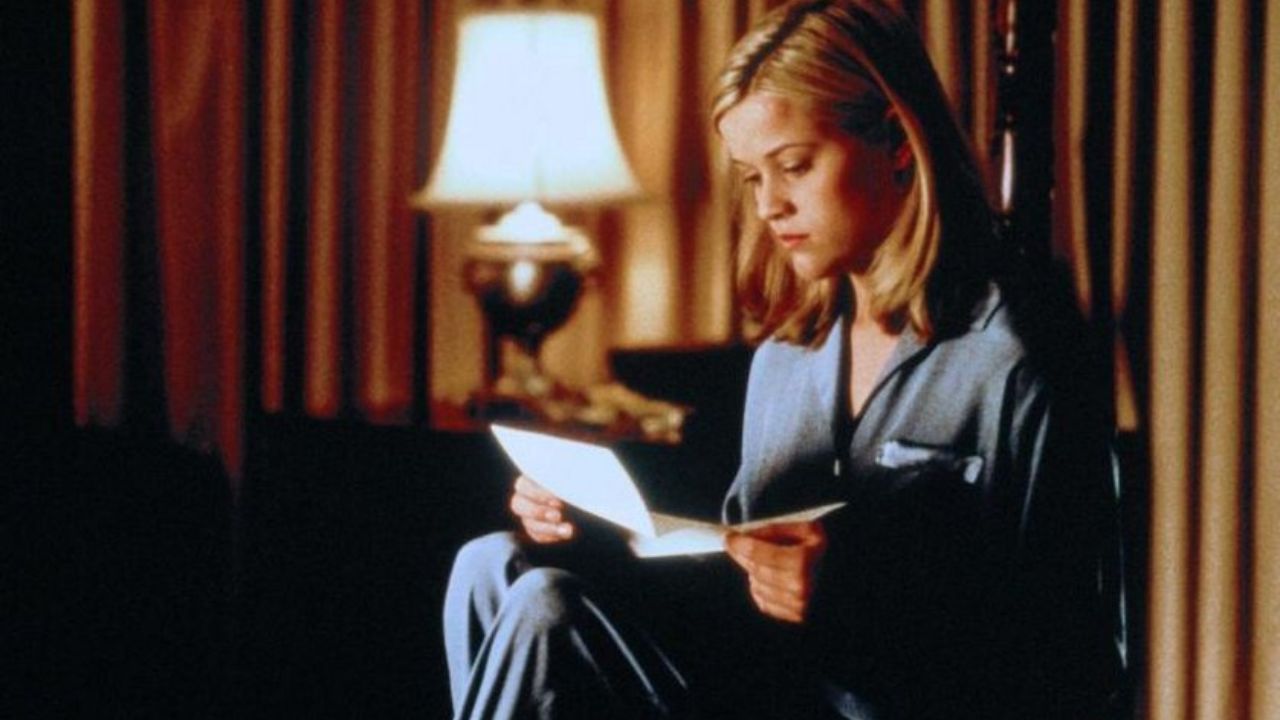 Das Bild zeigt eine Frau, die im Pijama gekleidet sitzt und einen Brief liest
