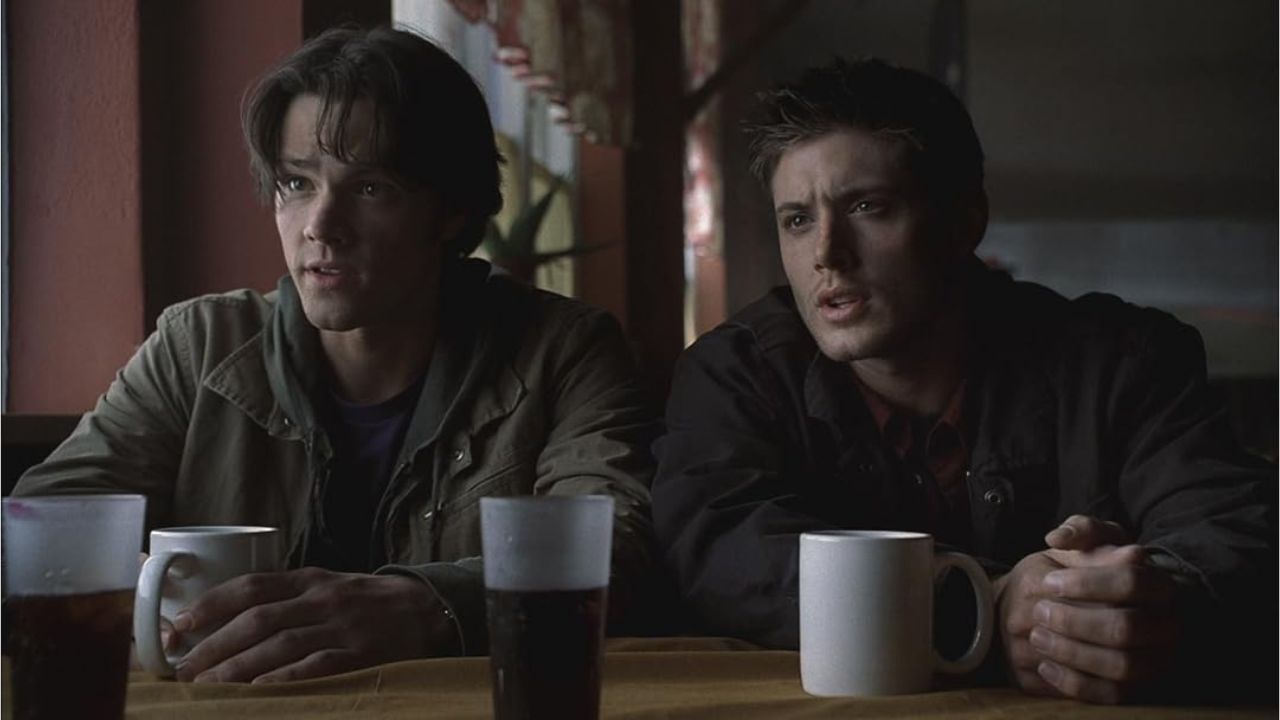 Supernatural Staffel 1: Auf dem Bild sind zwei Männer, die an einem Tisch sitzen. Vor ihnen stehen zwei Kaffeetassen und zwei Gläser mit Cola