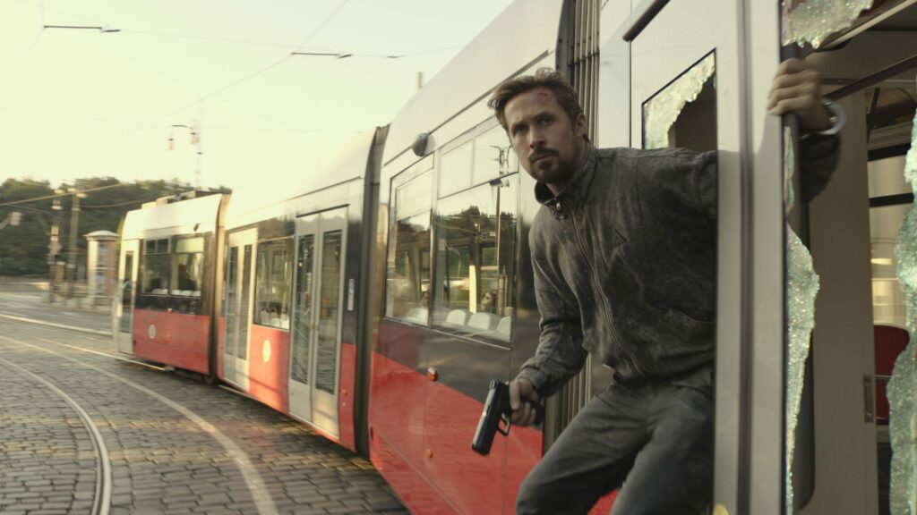 Die besten Action-Filme mit spektakulären Stunts: Auf dem Bild steht Ryan Gosling an der Tür einer fahrenden Tram Bahn.