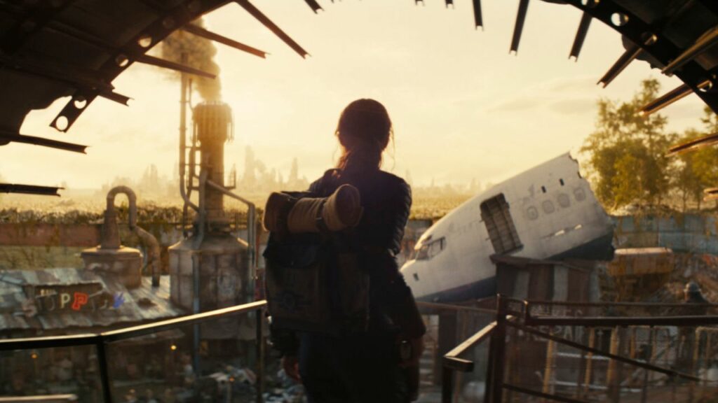 Auf dem Bild sieht man eine junge Frau, die gerade auf eine zerstörte Stadt zugeht