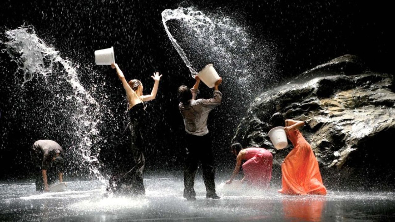 Auf dem Bild ist eine Gruppe von Menschen zu sehen, die Eimer in der Hand halten und sich gegenseitig mit Wasser nass spritzen