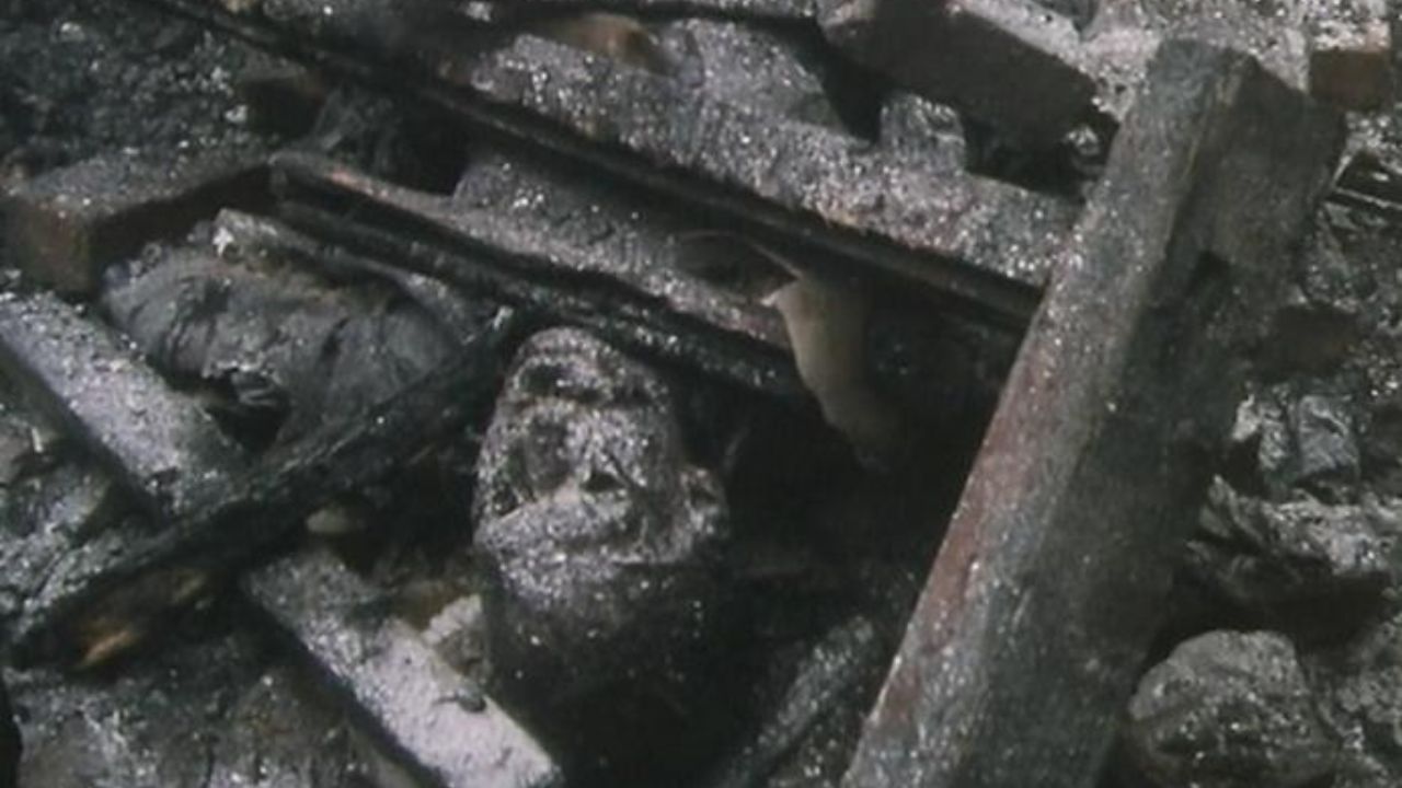 Das Bild zeigt einen verbrannten Körper unter Holztrümmern