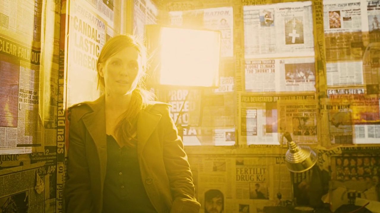 Children of Men: Das Bild zeigt eine Frau, die in einem gelben Licht steht. Die Wände hinter ihr sind mit Zeitungspapier tapeziert