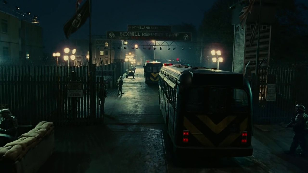 Children of Men: Auf dem Bild sind Busse zu sehen, die gerade durch ein Tor fahren. Es ist dunkel. Ein paar Soldaten gehen um die Busse herum