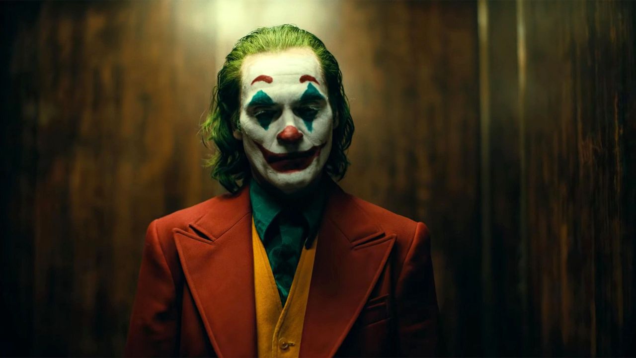 Joker: Das Bild zeigt einen Clown, der vor einer Holzwand steht und nachdenklich nach unten blickt