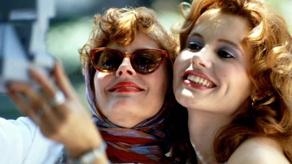 Thelma & Louise: Auf dem Bild sind zwei Frauen zu sehen, die eng beieinander sind um ein Foto von sich zu machen. Sie lächeln beide. Die Frau links trägt eine Sonnenbrille und ein Kopftuch