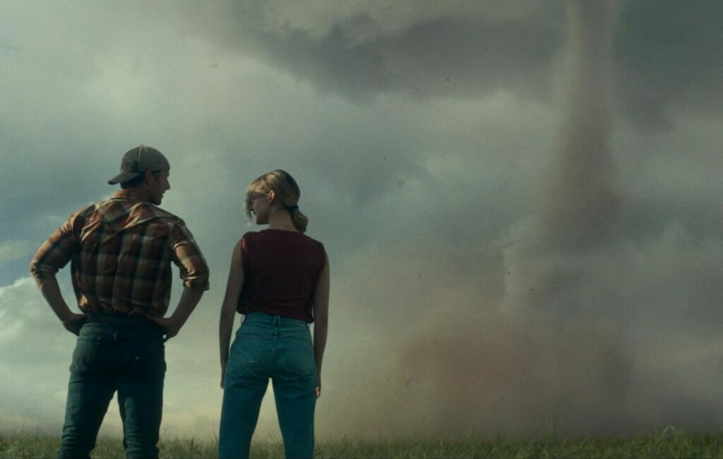 Glen Powell und Daisy Edgar-Jones bestaunen einen Tornado rechts im Bild. | Twisters