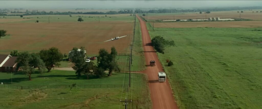 Landschaftsaufnahme einer braun-roten Landstraße auf der Autos fahren. | Twisters