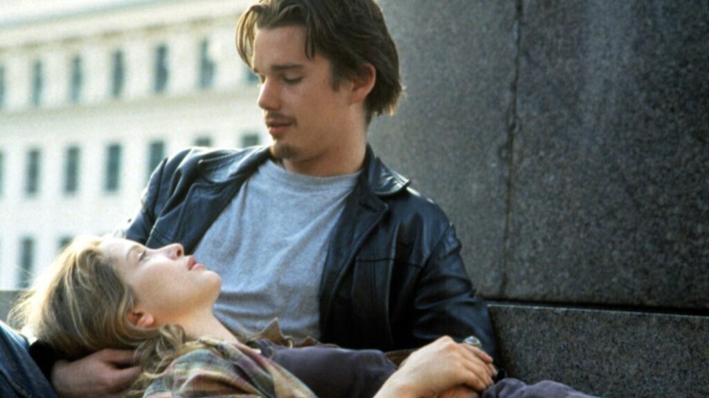 Before Sunrise: Auf dem Bild ist ein Mann und eine Frau zu sehen. Er lehnt an einer Wand und sie hat ihren Kopf auf seinem Schoß gebettet | Top 5 Wohlfühlfilme