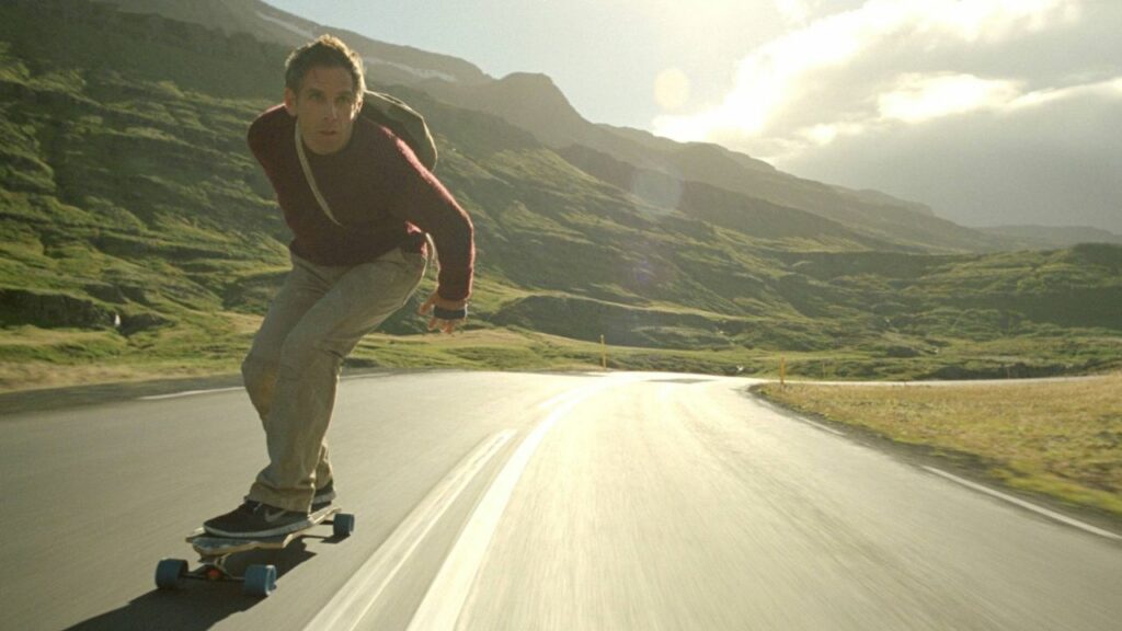 Das erstaunliche Leben des Walter Mitty: Auf dem Bild ist ein Mann auf einem Longboard zu sehen und fährt eine Straße entlang | Die 5 besten Filme im Grünen