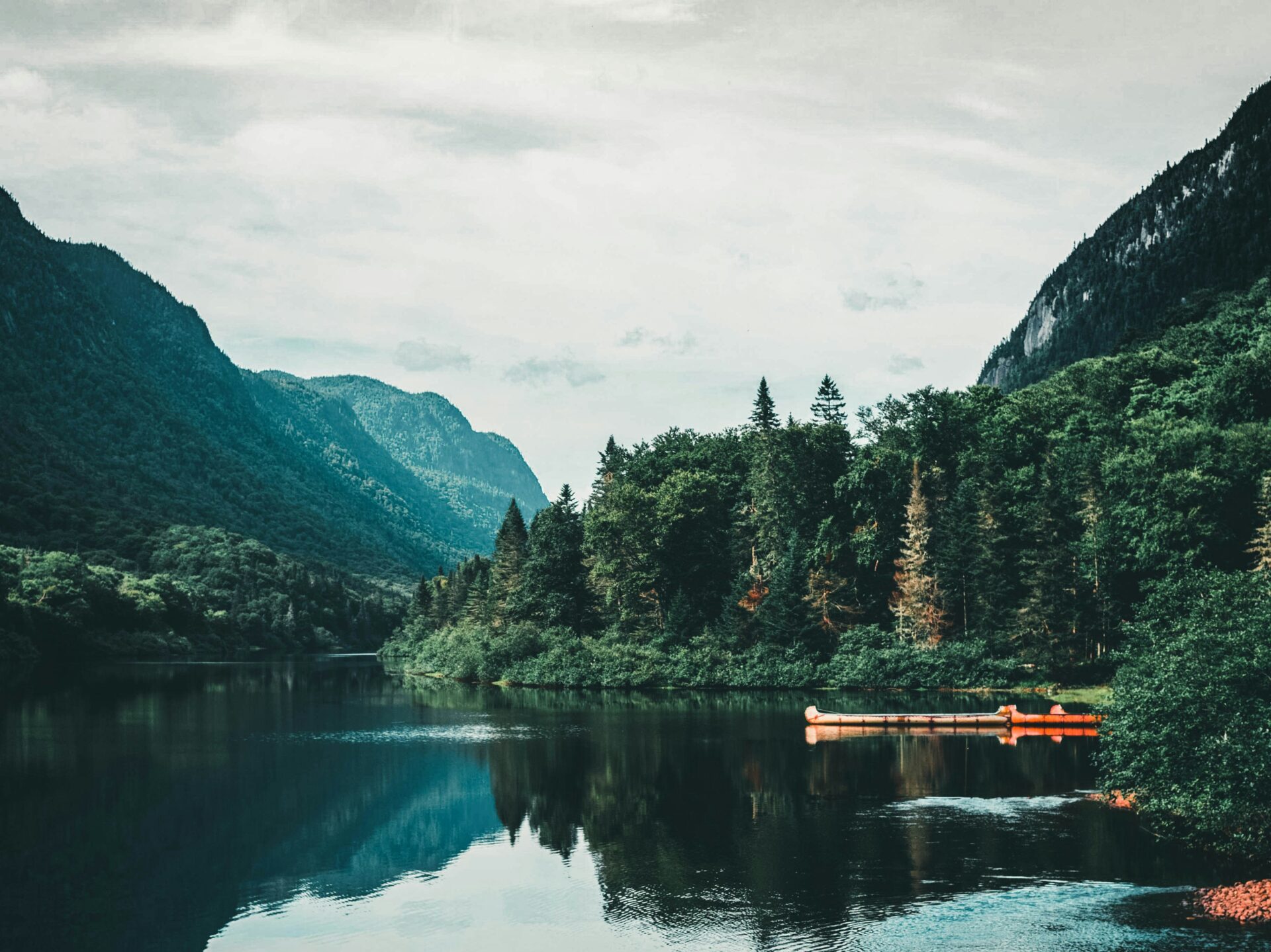 Auf dem Bild ist ein See auf dem lange Kanus zu sehen sind. Im Hintergrund sind Wälder und Berge zu sehen | Die 5 liebsten Buch Charaktere