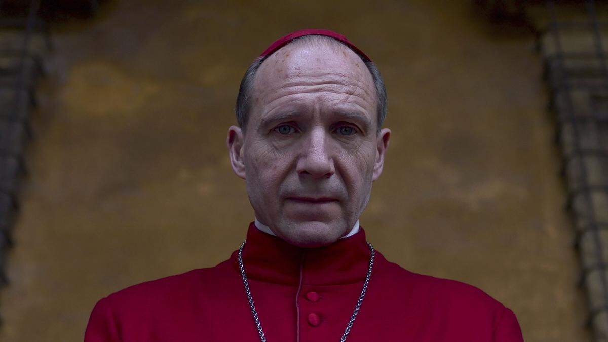 Auf dem Bild ist Ralph Fiennes in der roten Robe zu sehen