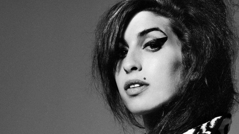 Schwarz-Weiß-Porträt von Amy Winehouse mit voluminösen, toupierten Haaren. Sie trägt stark betonten Lidstrich im Retro-Stil und hat ein auffälliges Muttermal über ihrer Lippe. Ihr Blick ist leicht seitlich gerichtet, mit einem intensiven und ausdrucksstarken Ausdruck. Die Beleuchtung hebt ihre Gesichtszüge kontrastreich hervor. | Die 5 besten Biopics