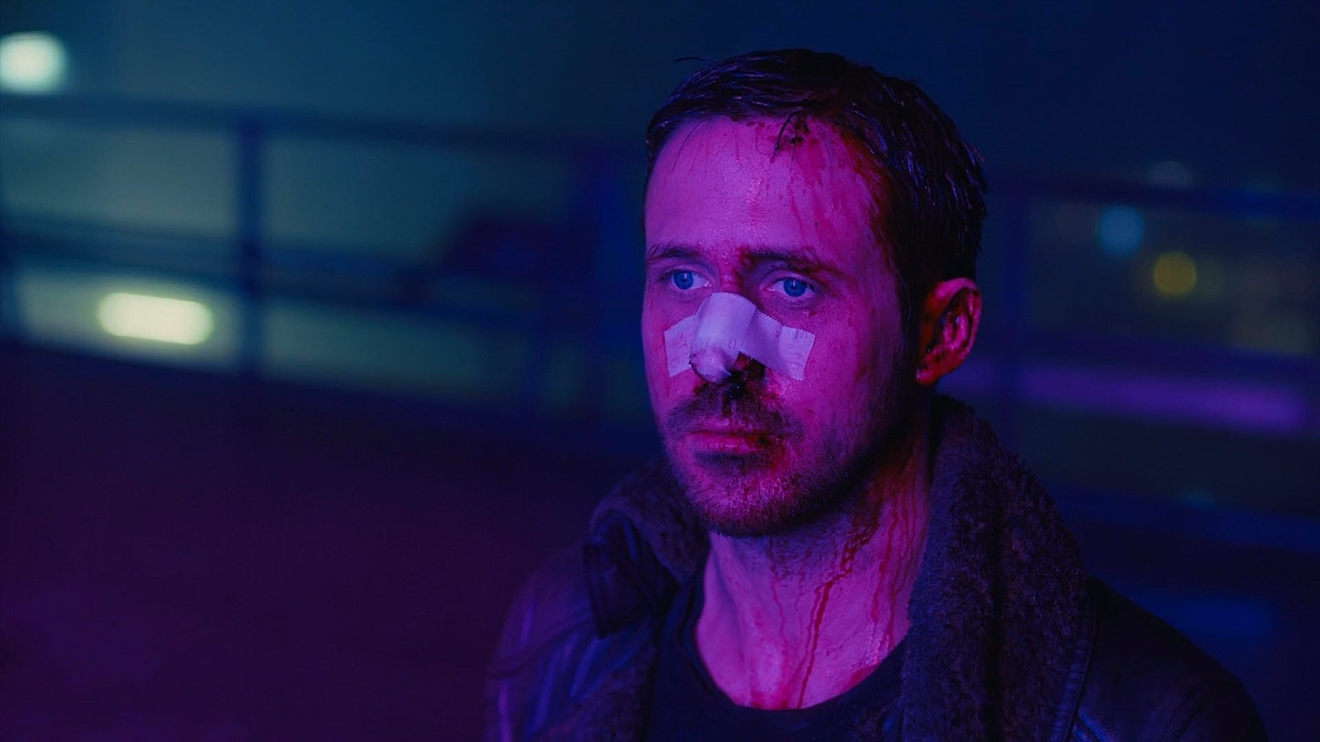 Blade Runner 2049: Das Bild zeigt Officer K in lilafarbenes Neonlicht getaucht. Er blutet im Gesicht und hat ein Pflaster auf seiner Nase. Sein Blick ist traurig | Die 5 besten Regieführenden des 21. Jahrhunderts
