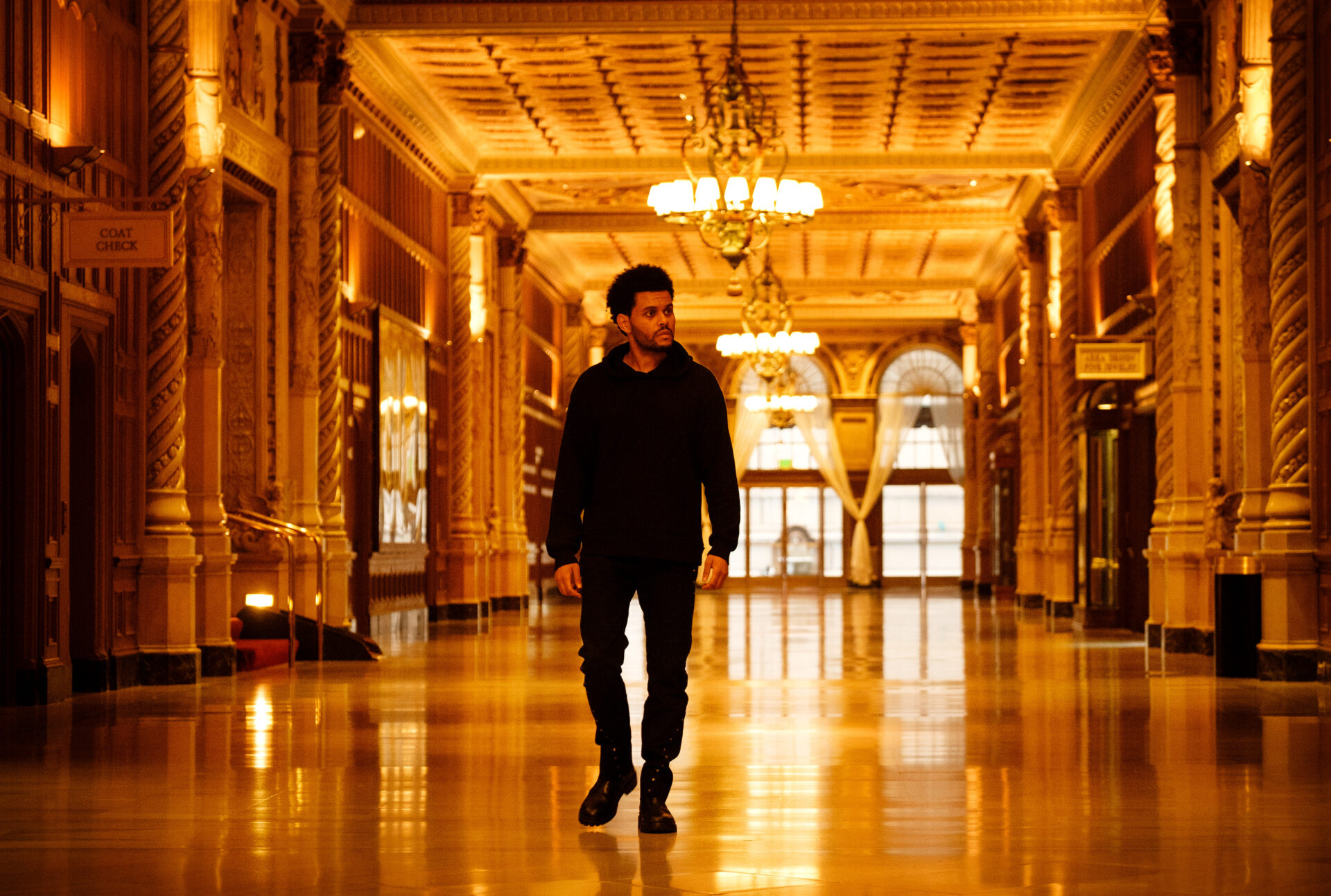 Abel Tesfaye läuft durch einen schmuckvoll augestatteten Flur, der durch mehrere Kronleuchter in ein gelbes Licht getaucht wird. | Top 5 Filme die besser sind als ihr Ruf