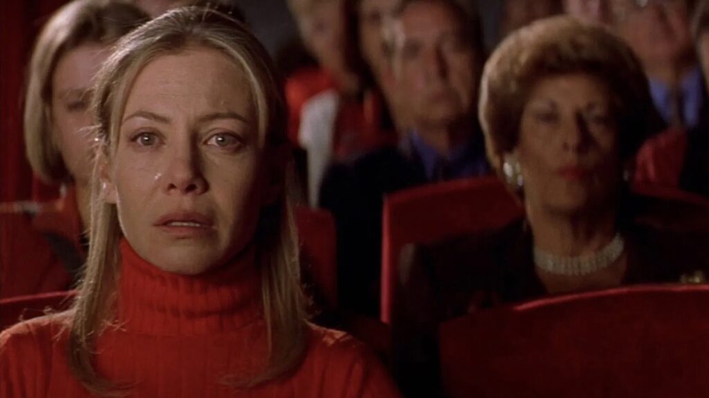 Das Bild zeigt eine Frau in einem Kinosaal, die auf die Leinwand schaut und weint | 90er Jahre Kino: Die 5 besten Filme aus den 90er Jahren
