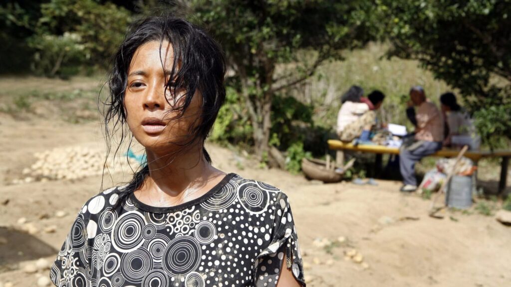 Bok-nam im Film "Bedevilled" schaut in die Ferne, während im Hintergrund andere Frauen im Schatten sitzen | Die 5 besten Filme aus Südkorea