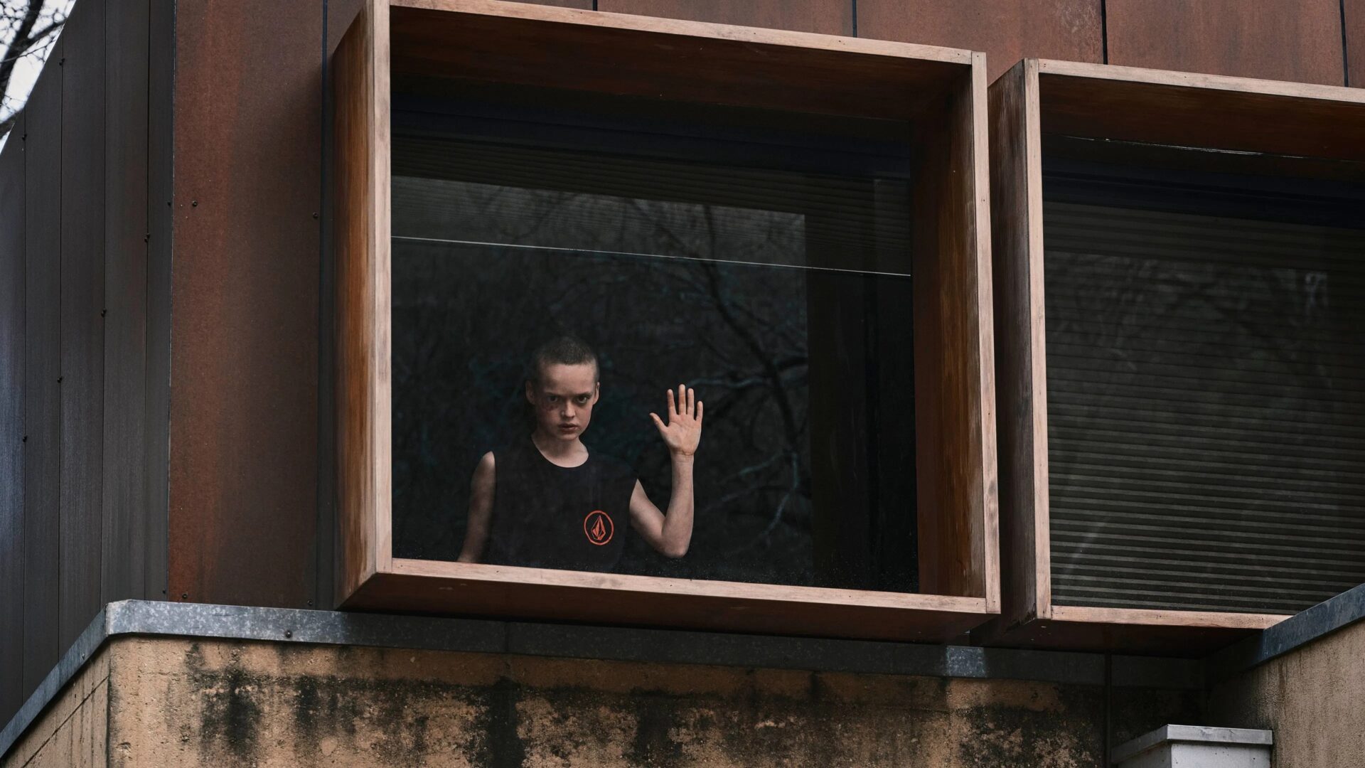 Das Bild zeigt Jonah Wren Phillips als Oliver, am Fenster stehend