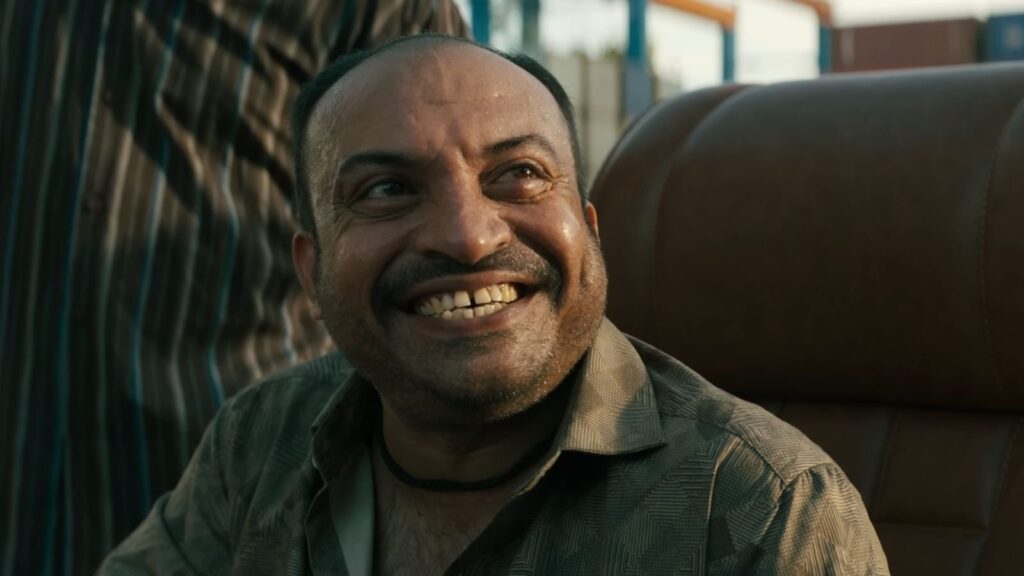 Das Bild zeigt einen diabolisch grinsenden Soubin Sahir aus dem Film Coolie.