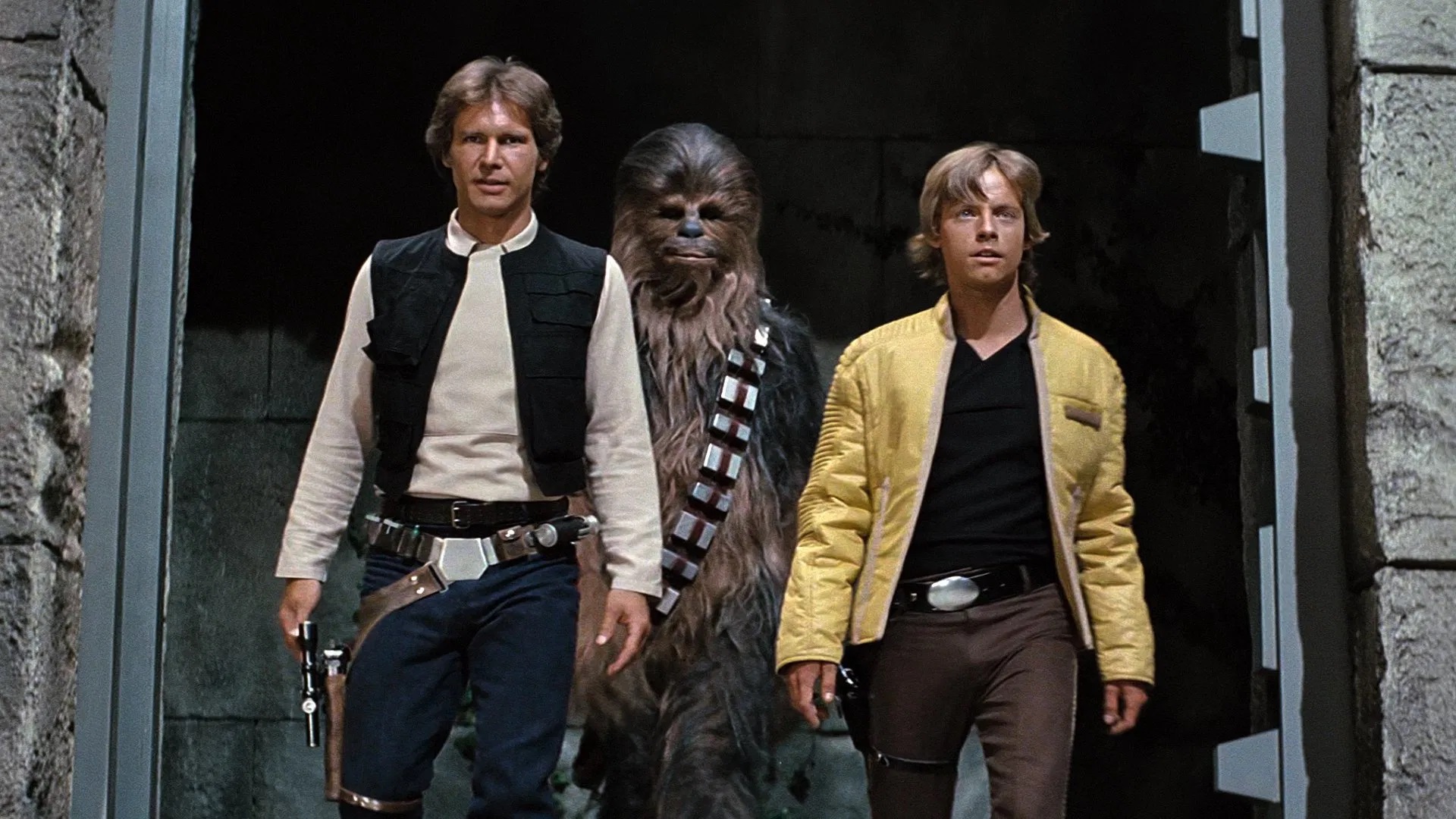 Das Bild zeigt Han Solo (Harrison Ford), Chewbacca (Peter Mayhew) und Luke Skywalker (Mark Hamill)