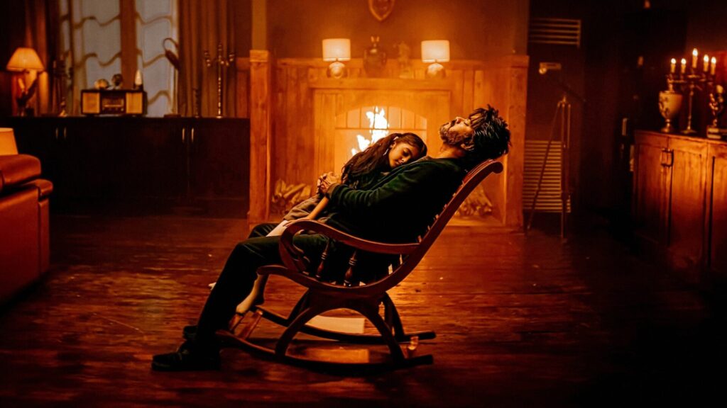 In orangenem Licht sitzt ein Mann mit einem Kind auf einem Schaukelstuhl. Szene aus dem Film "Leo".