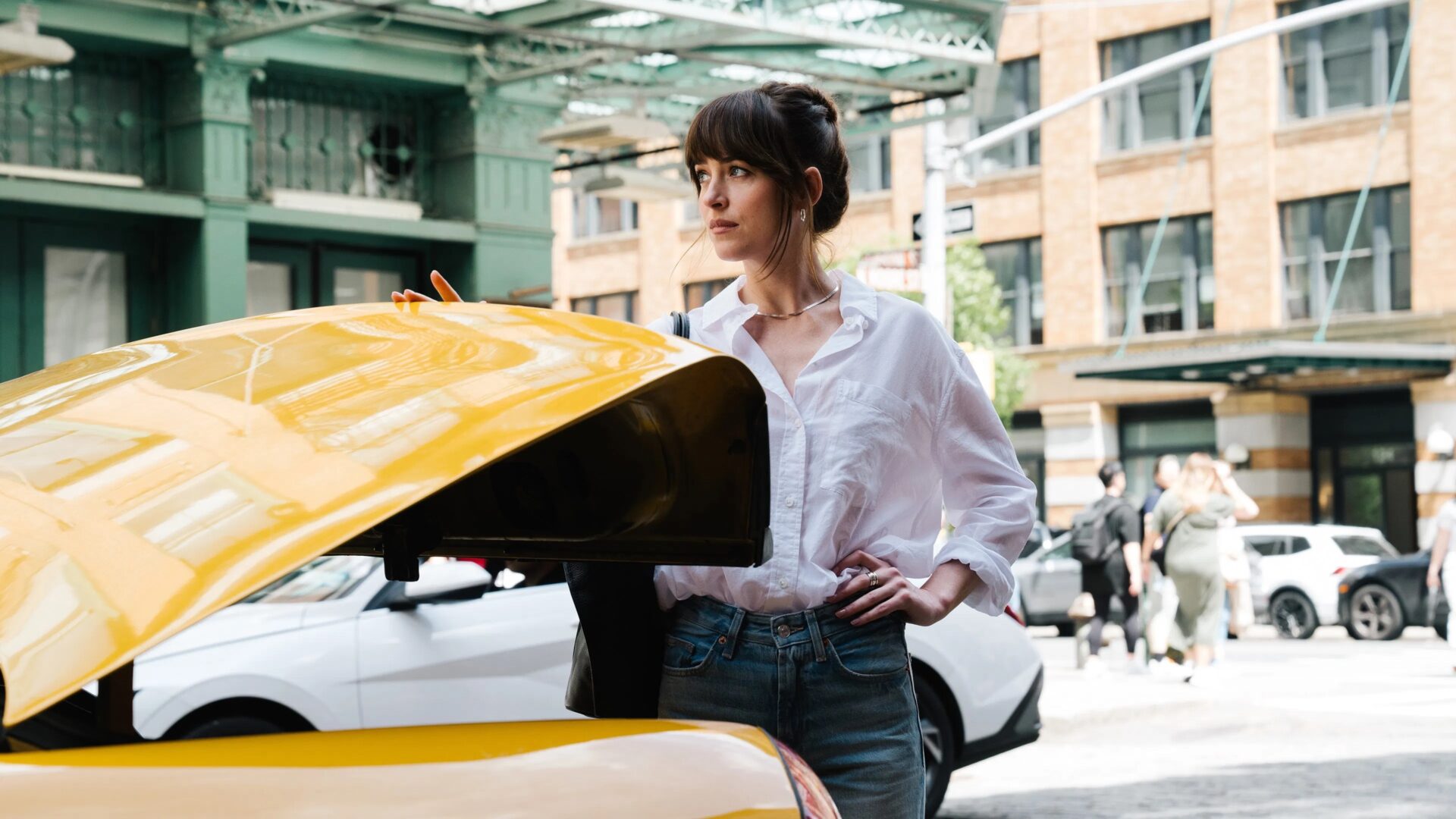 Das Bild zeigt Dakota Johnson am Kofferraum eines Taxis