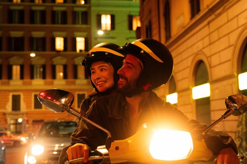 Yaxi Liu und Enrico Borello sitzen in der Nacht auf einem Moped. Szene aus dem Film "Kung Fu in Rome".