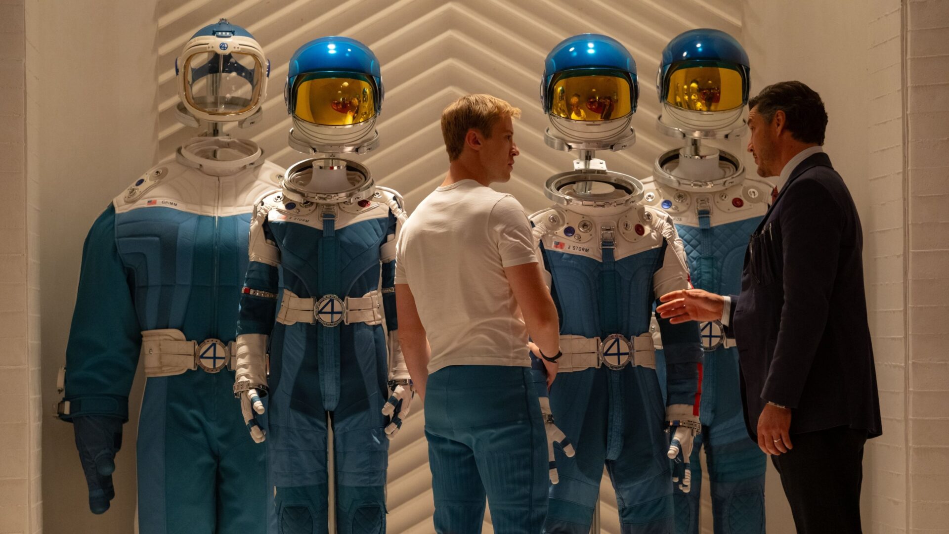 Johnny Storm und Reed Richards stehen vor den 4 Raumanzügen der fantastischen Vier. | The Fantastic Four: First Steps