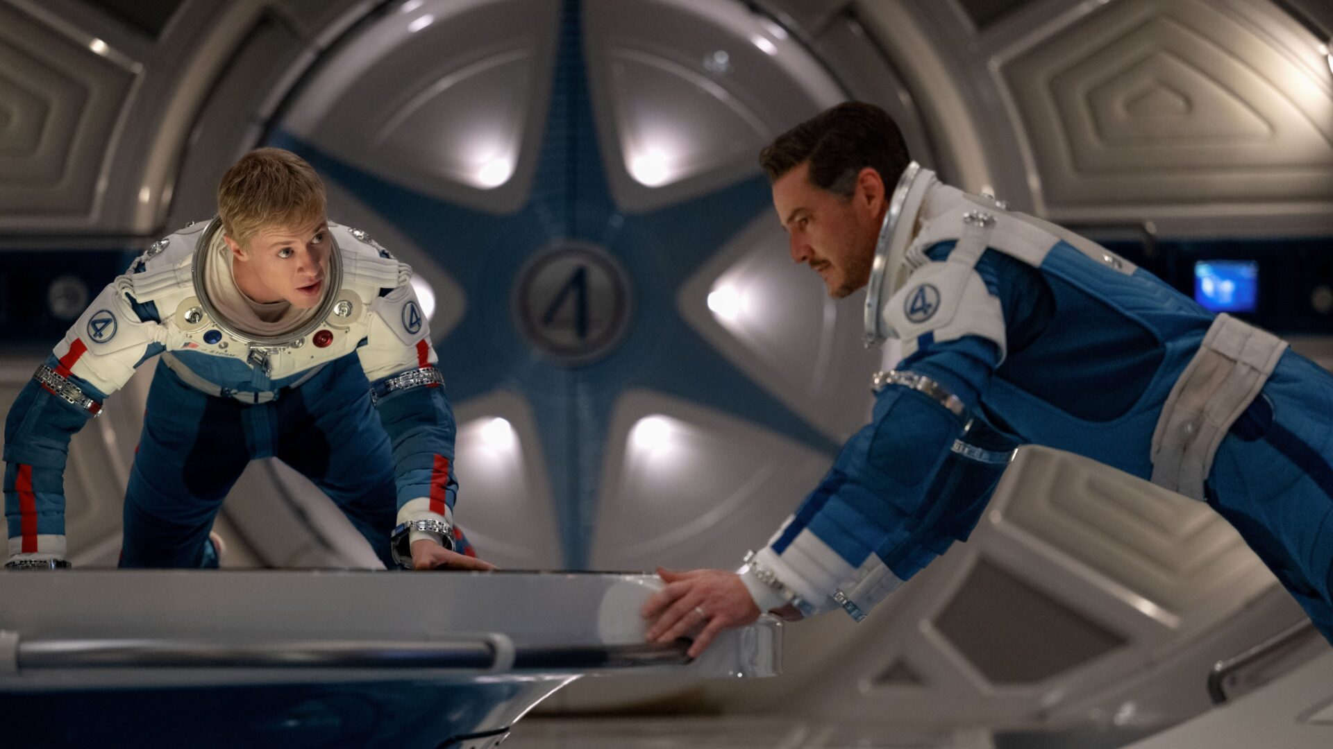 Johnny Storm und Reed Richards schweben mit Raumanzügen in einem Raumschiff in Schwerelosigkeit.