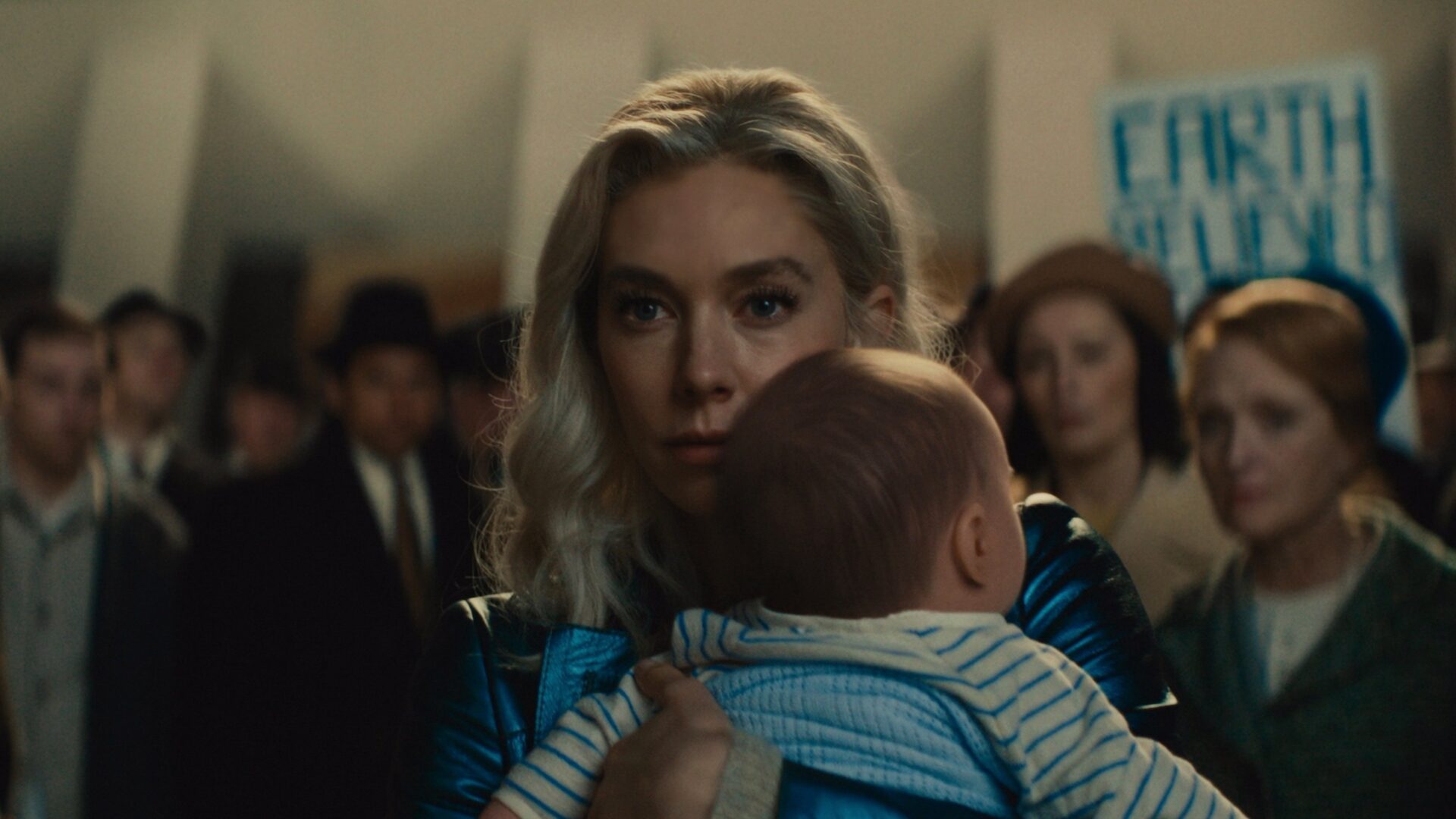 Susan Storm hält ihr Baby in der Hand. Hinter ihr eine Menschenmenge. | The Fantastic Four: First Steps