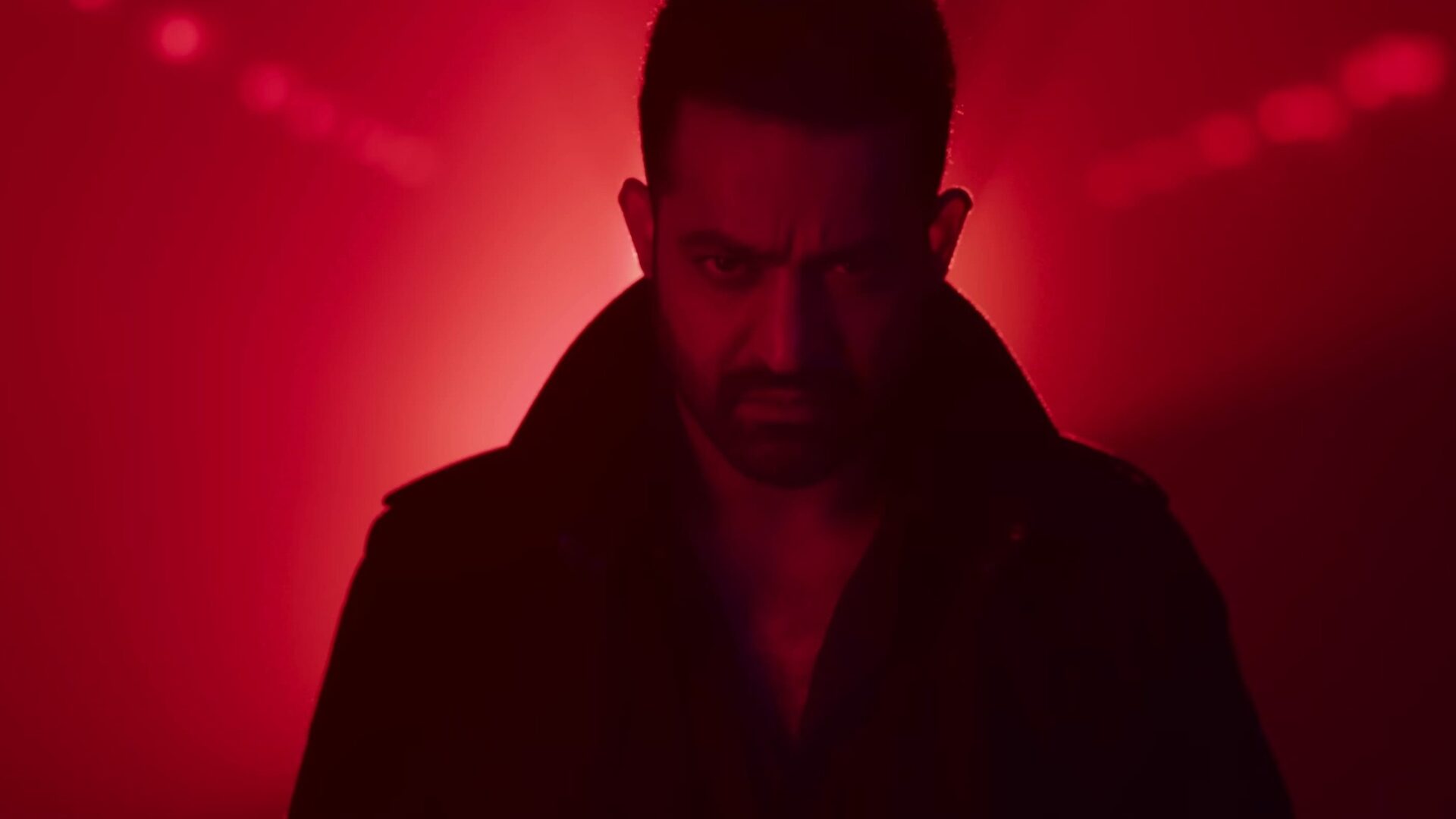 Vikram im schwarzen Mantel. Im Hintergrund rotes Licht. | War 2 – Filmkritik