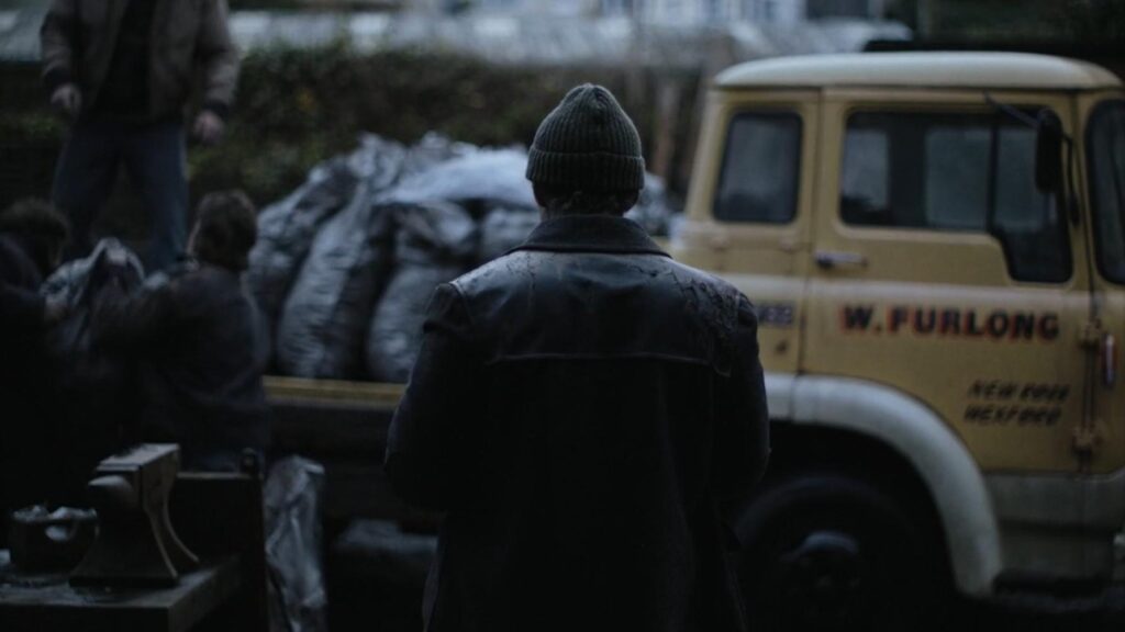 Cillian Murphy steht vor einem gelben Laster mit dem Rücken zur Kamera. Szene aus dem Film Kleine Dinge wie diese.