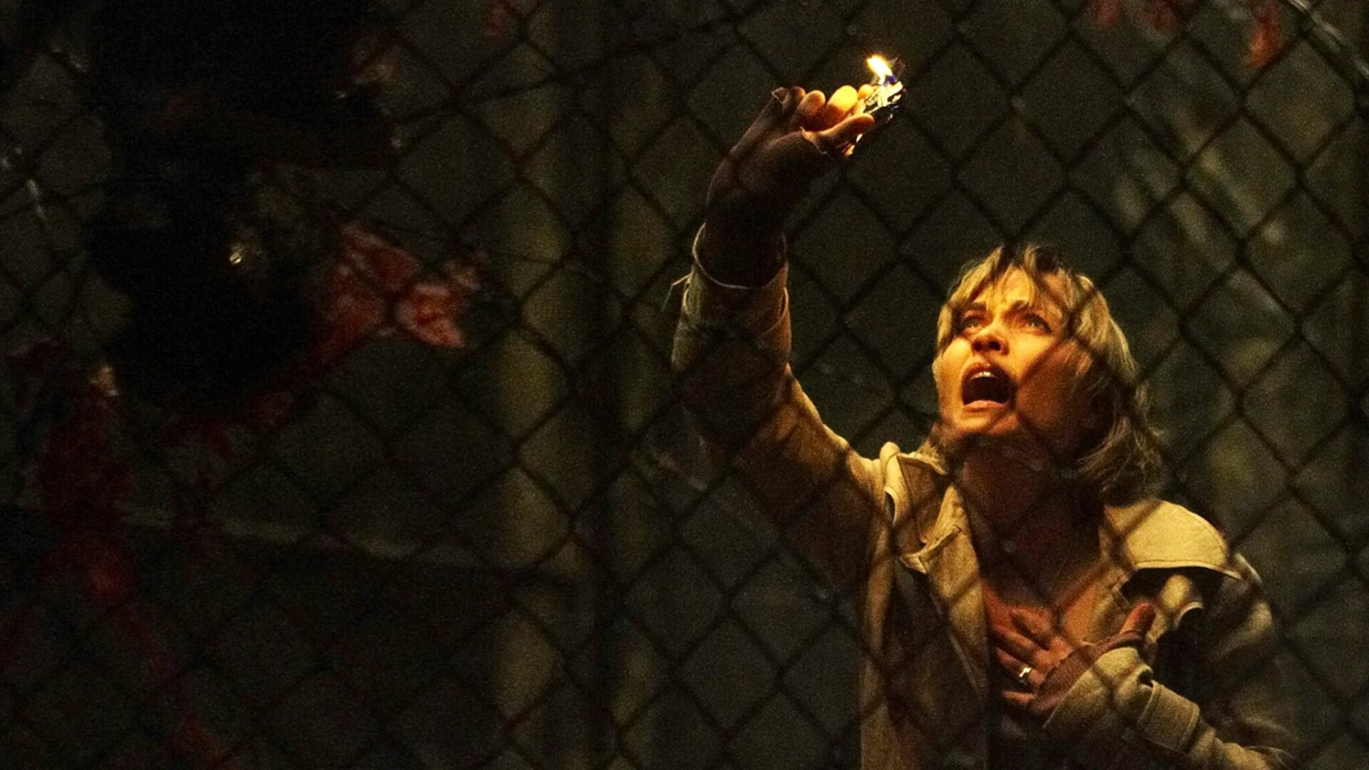 Das Bild zeigt eine Frau hinter einem Maschendrahtzaun die erschrocken auf etwas vor sich blickt | Top 5 Horror Videospiel Verfilmungen