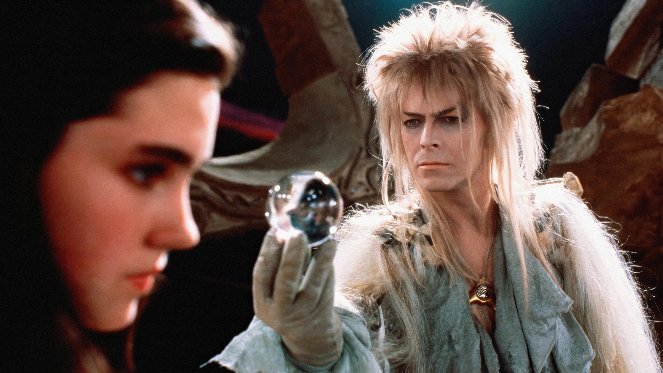 David Bowie im Film "Labyrinth" er hält Jennifer Connelly im Vordergrund eine Glaskugel entgegen