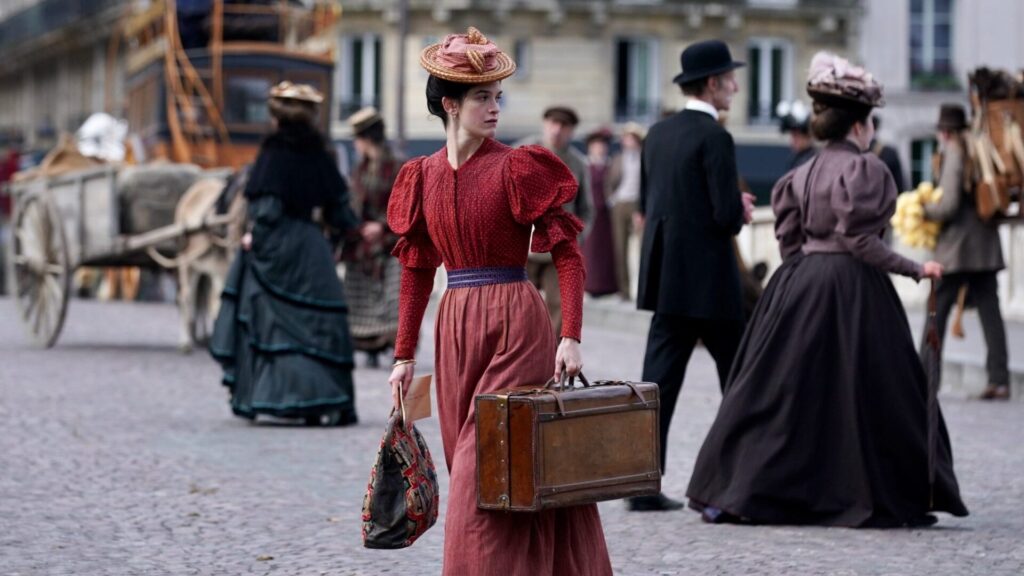 Eine Frau in einem roten Kleid eilt im 19. Jahrhundert über die Straße.